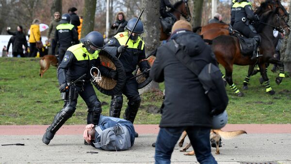 Polícia luta com um manifestante durante protesto contra as restrições para conter a COVID-19 em Haia, Países Baixos, 14 de março de 2021 - Sputnik Brasil