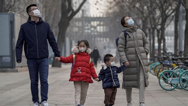 Um casal e seu filho em uma rua de Pequim usando máscaras faciais para ajudar a conter a disseminação do coronavírus  - Sputnik Brasil