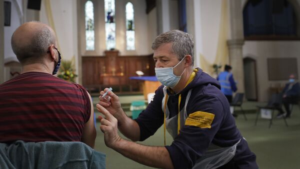 Um vacinador administra o imunizante da AstraZeneca na Igreja de St John, em Ealing, Londres, em 16 de março de 2021 - Sputnik Brasil