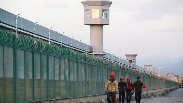Os trabalhadores caminham pela cerca do perímetro do que é oficialmente conhecido como um centro de educação de habilidades vocacionais em Dabancheng, na Região Autônoma Uigur de Xinjiang, China, 4 de setembro de 2018 - Sputnik Brasil