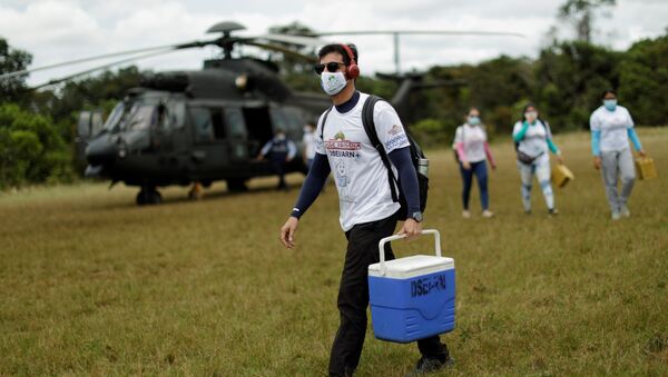 Funcionário de saúde carrega lote com CoronaVac após desembarcar de helicóptero na aldeia Tacarua Igarapé, na cidade de São Gabriel da Cachoeira, no Amazonas - Sputnik Brasil