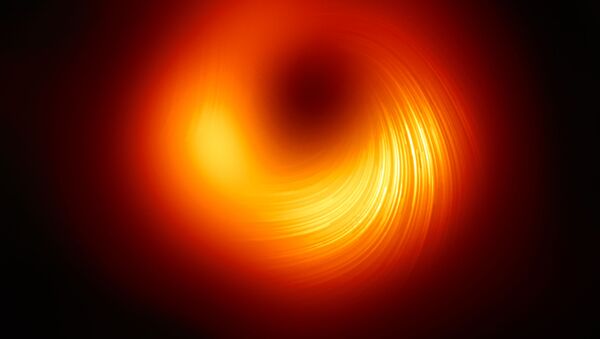 Imagem do buraco negro da galáxia M87. As linhas visíveis mostram a direção da polarização, diretamente ligada ao campo magnético do buraco negro - Sputnik Brasil