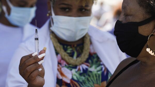 Enfermeira mostra seringa para mulher em Duque de Caxias, no Rio de Janeiro, em 29 de março de 2021 - Sputnik Brasil