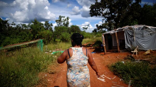 Mulher caminha perto de barraco onde vive nas proximidades do Palácio do Planalto, em Brasília - Sputnik Brasil