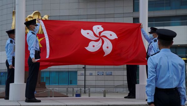 Policiais seguram as bandeiras de China e Hong Kong durante a cerimônia de abaixamento de bandeira, em Hong Kong, China, 30 de março de 2021 - Sputnik Brasil