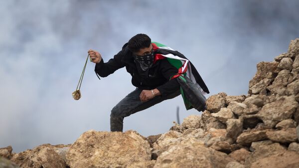 Manifestante palestino usa uma funda para atirar pedras contra soldados israelenses durante um protesto contra os assentamentos israelenses, na vila de al-Mughayyir, perto da cidade de Ramallah, na Cisjordânia, em 15 de janeiro de 2021 - Sputnik Brasil