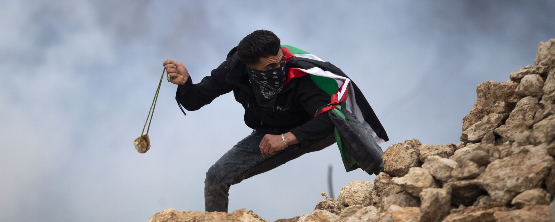 Manifestante palestino usa uma funda para atirar pedras contra soldados israelenses durante um protesto contra os assentamentos israelenses, na vila de al-Mughayyir, perto da cidade de Ramallah, na Cisjordânia, em 15 de janeiro de 2021 - Sputnik Brasil, 1920, 17.07.2022