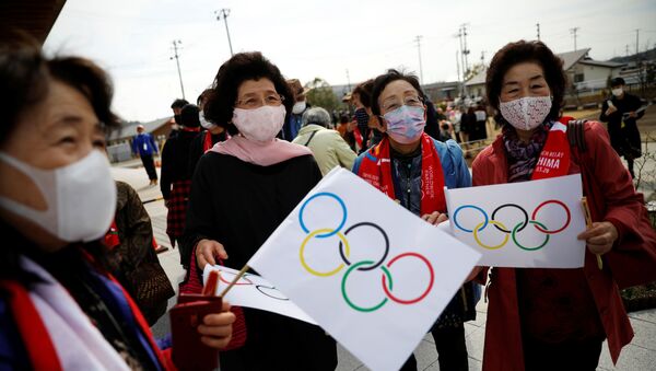 Pessoas com bandeiras olímpicas no percurso de passagem da Tocha Olímpica Tóquio 2020, Japão, 25 de março de 2021 - Sputnik Brasil