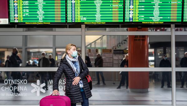 Em Varsóvia, na Polônia, uma viajante de máscara de proteção contra a COVID-19 caminha no saguão de desembarque do aeroporto Chopin, em 19 de março de 2020 - Sputnik Brasil