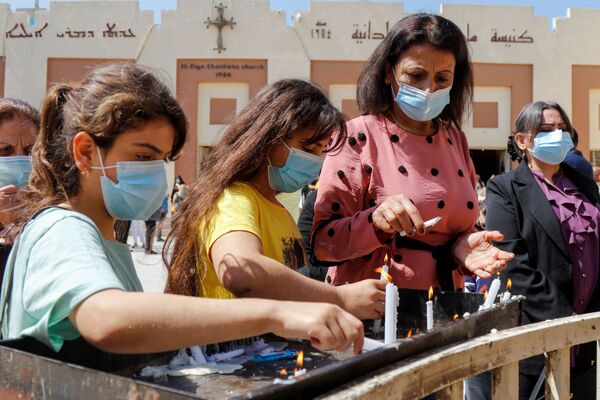 Pessoas acendem velas após a missa de Páscoa fora de igreja em meio à pandemia do novo coronavírus em Bagdá, Iraque, 4 de abril de 2021 - Sputnik Brasil