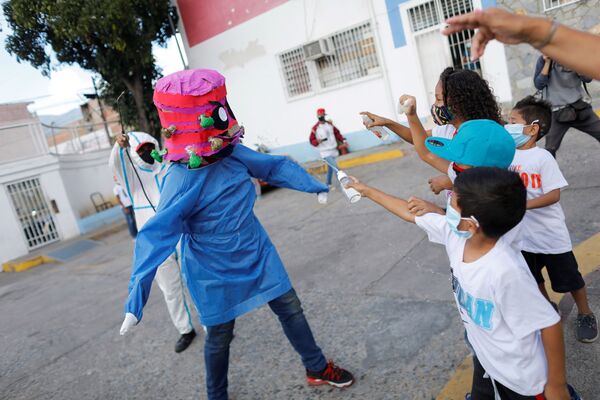 Crianças jogam álcool em gel em uma pessoa fantasiada de coronavírus durante a queima tradicional de Judas como parte das celebrações da Semana Santa em Caracas, Venezuela, 4 de abril de 2021 - Sputnik Brasil