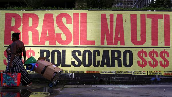 Mulher caminha em frente a uma faixa que diz: Brasil na UTI, em referência ao presidente Jair Bolsonaro e a alta dos preços dos produtos básicos em São Paulo, 8 de março de 2021 - Sputnik Brasil