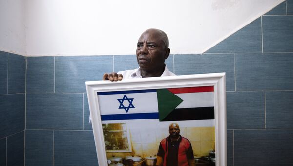 O migrante sudanês Attom Alialdom segura uma foto de seu antigo restaurante decorado com bandeiras sudanesas e israelenses, do lado de fora de sua casa no sul de Tel Aviv, Israel, domingo, 25 de outubro de 2020 - Sputnik Brasil