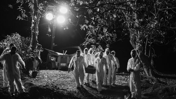 Sepultadores, usando trajes de proteção, carregam caixão com vitima da COVID-19, iluminados por holofotes no Cemitério Vila Formosa, na zona leste de São Paulo. - Sputnik Brasil