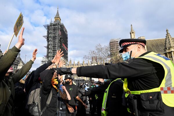Manifestantes levantam suas mãos enquanto enfrentam policiais durante um protesto em Londres, Reino Unido, 3 de abril de 2021 - Sputnik Brasil