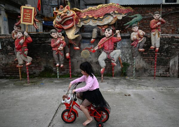 Menina passa de bicicleta ao lado da instalação Dança de Leão do artista Nguyen Xuan Lam, em Hanoi, 14 de abril de 2021 - Sputnik Brasil