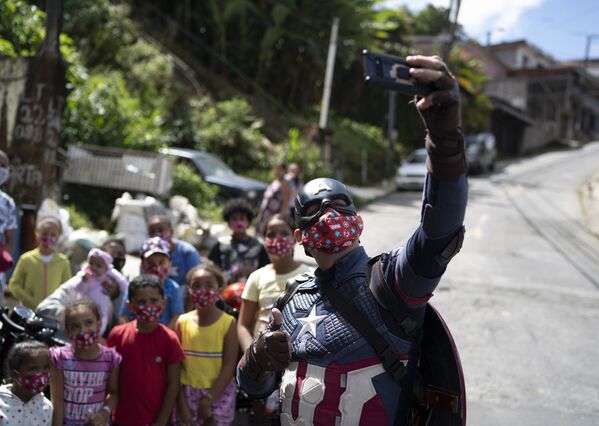 Policial militar fantasiado de Capitão América tirando selfie com crianças em Petrópolis, Rio de Janeiro, 14 de abril de 2021 - Sputnik Brasil