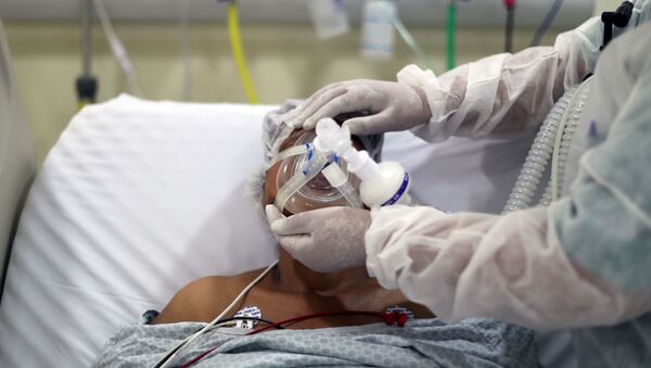 Em São Paulo, uma fisioterapeuta ajusta uma máscara de oxigênio em um paciente com COVID-19, em uma UTI do Hospital Municipal de Parelheiros, em 8 de abril de 2021 - Sputnik Brasil
