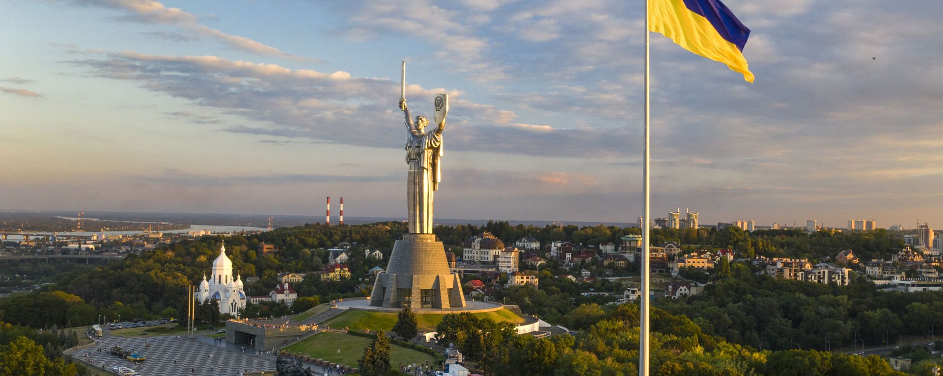 A maior bandeira da Ucrânia está hasteada a cerca de 90 metros acima da cidade, pois foi instalada na véspera do Dia da Bandeira do Estado, com o Monumento à Pátria Mãe no centro, em Kiev, Ucrânia, sábado, 22 de agosto de 2020 - Sputnik Brasil, 1920, 07.03.2023