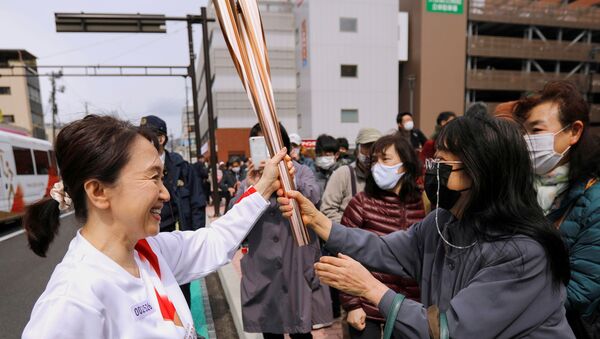 Espectadores admiram a tocha olímpica durante o segundo dia de revezamento em Fukushima, no Japão, em 26 de março de 2021 - Sputnik Brasil