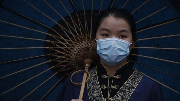 Uma mulher vestida com um traje tradicional usa uma máscara protetora para ajudar a conter a disseminação do novo coronavírus visita o popular ponto turístico de Nanluonguxiang depois de reaberto para turistas após o surto de coronavírus em Pequim, domingo, 3 de maio de 2020 - Sputnik Brasil