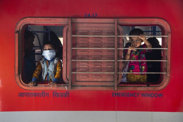 Meninos olham pela janela de trem na estação ferroviária em Guwahati, Índia, 19 de abril de 2021 - Sputnik Brasil