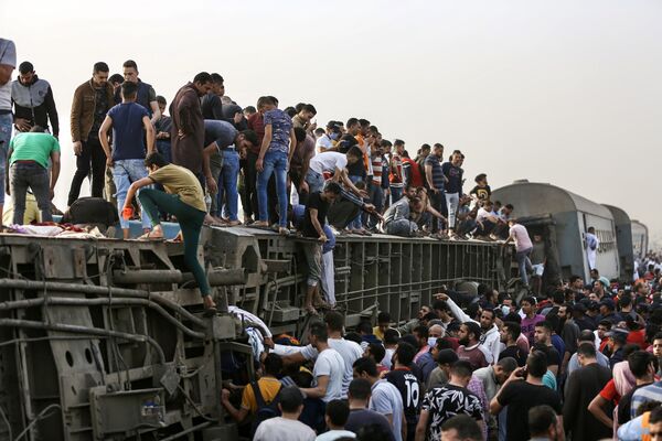 Pessoas sobem em carruagem de trem virada após o acidente na cidade de Toukh, Egito, 19 de abril de 2021. O trem descarrilou, deixando 11 pessoas mortas e 98 feridas - Sputnik Brasil