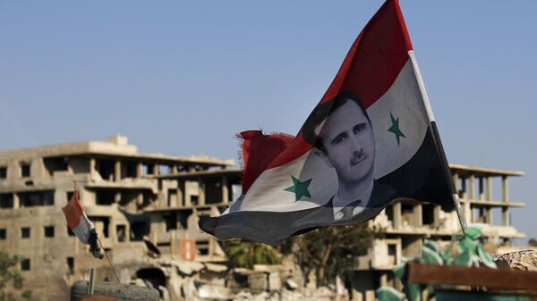 Bandeira nacional da Síria com foto de Bashar al-Assad, presidente do país, tremula em posto de controle do Exército sírio na cidade de Douma, perto de Damasco, na Síria, em 15 de julho de 2018 - Sputnik Brasil