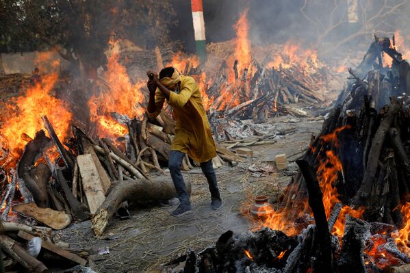 Em Nova Deli, na Índia, um homem corre em meio a piras funerárias em meio a uma cremação em massa de corpos de pacientes infectados com a COVID-19, em 26 de abril de 2021 - Sputnik Brasil
