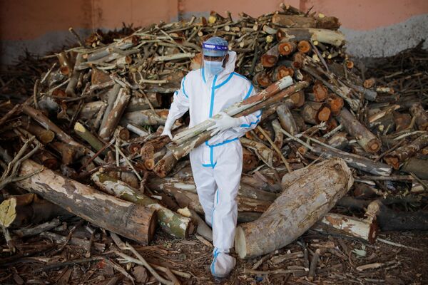 Em Nova Deli, na Índia, um homem carrega madeira para preparar piras funerárias em meio em um crematório para corpos de pacientes infectados com a COVID-19, em 26 de abril de 2021 - Sputnik Brasil