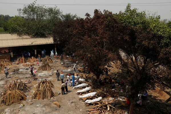 Em Nova Deli, na Índia, pessoas preparam piras funerárias para a cremação em massa de corpos de pacientes infectados com a COVID-19, em 26 de abril de 2021 - Sputnik Brasil
