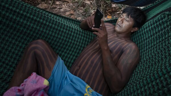 Indígena Kayapó checa seu celular enquanto descansava em uma rede perto de Novo Progresso, no estado do Pará, em setembro de 2019 - Sputnik Brasil