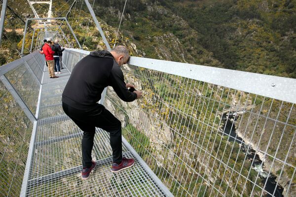 Homem tira foto da paisagem vista entre a grade protetora da 516 Arouca, ponte suspensa para pedestres, a mais longa do mundo, em Arouca, Portugal, 29 de abril de 2021 - Sputnik Brasil