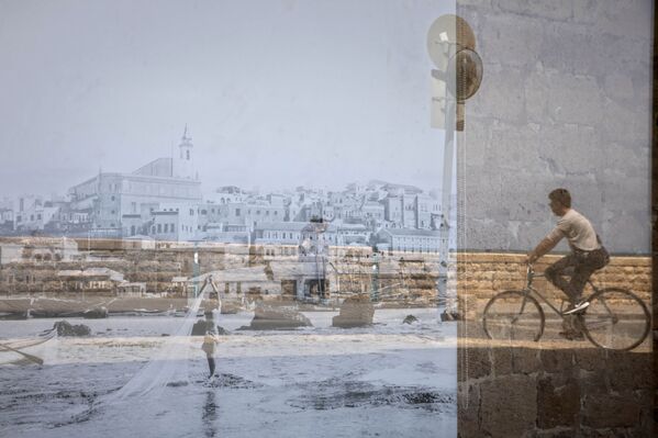 Homem passa de bicicleta sendo refletido em uma foto antiga de Jafa exibida em uma janela, no bairro de Jafa de Tel Aviv, Israel, 21 de abril de 2021 - Sputnik Brasil