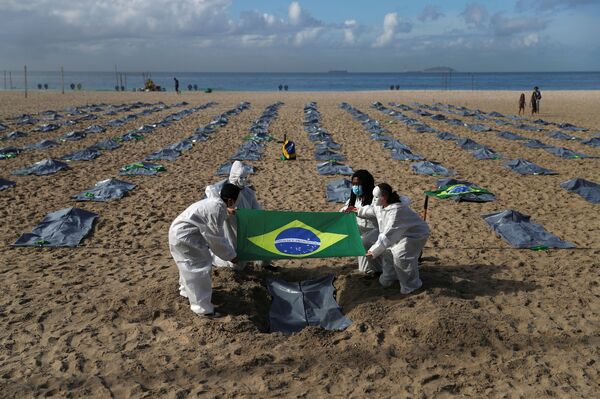 Ativistas da organização não governamental Rio de Paz carregam a bandeira brasileira, enquanto exibem centenas de sacos de plástico representando mortos e relembrando os 400 mil óbitos pela COVID-19, durante protesto contra a política de Jair Bolsonaro para a COVID-19, praia de Copacabana, Rio de Janeiro, Brasil, 30 de abril de 2021 - Sputnik Brasil