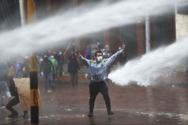 Manifestante faz gesto contra o canhão d’água da polícia durante os protestos antigovernamentais em Bogotá, Colômbia, 5 de maio de 2021 - Sputnik Brasil