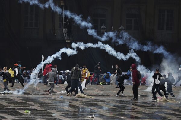 Manifestantes antigovernamentais jogam bombas de gás lacrimogêneo à polícia durante confrontos em Bogotá, Colômbia, 5 de maio de 2021 - Sputnik Brasil