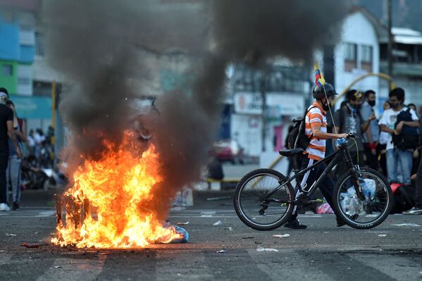 Manifestantes passam por uma barricada em chamas bloqueando a rua durante os protestos contra o governo do presidente Iván Duque em Cali, Colômbia, 5 de maio de 2021 - Sputnik Brasil