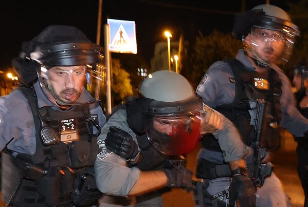 Policial israelense ferido é ajudado durante confrontos com manifestantes palestinos no bairro Sheikh Jarrah em Jerusalém Oriental, 7 de maio de 2021 - Sputnik Brasil