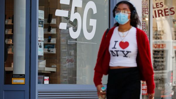Mulher usando máscara facial protetora passa por placa de rede de dados 5G em uma loja de telefonia móvel em Paris, França, 22 de abril de 2021 - Sputnik Brasil