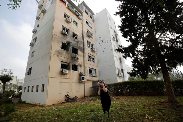Mulher caminha perto de um prédio residencial danificado por um foguete lançado da Faixa de Gaza - Sputnik Brasil