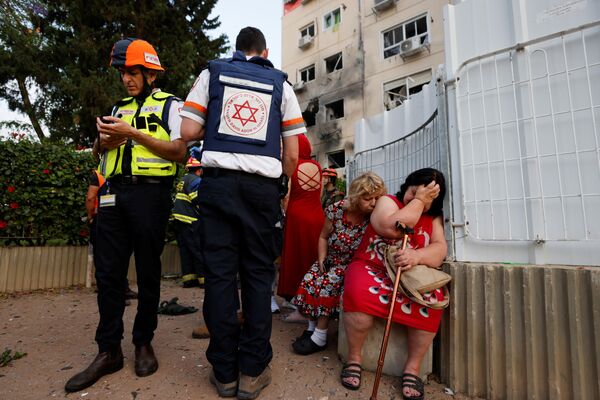 Médicos israelenses atendem mulheres perto de uma construção danificada por um foguete lançado da Faixa de Gaza - Sputnik Brasil