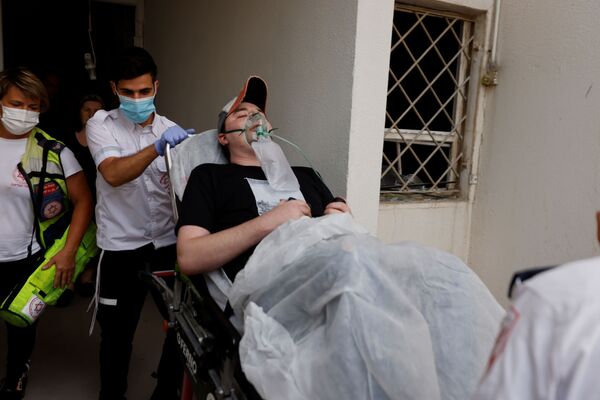 Médicos israelenses evacuam um homem ferido após foguete lançado de Gaza atingir prédio residencial no sul de Israel - Sputnik Brasil