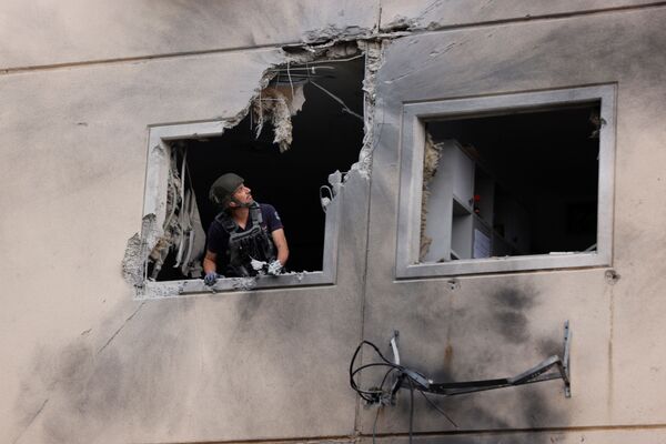Especialista do esquadrão antibombas da polícia de Israel observa pela janela de um prédio residencial danificado após ser atingido por um foguete lançado da Faixa de Gaza, no dia 11 de maio de 2021 - Sputnik Brasil