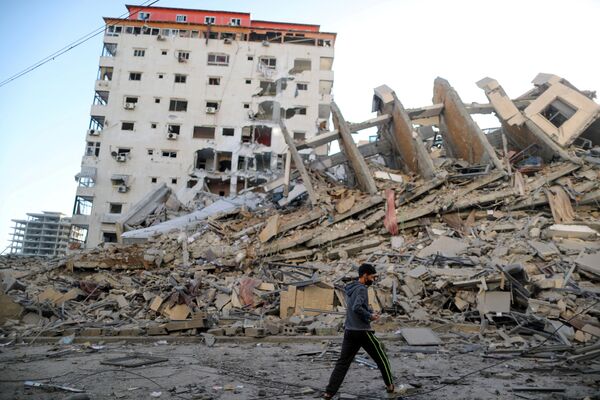 Garoto palestino caminha ao lado das ruínas de um prédio, que foi destruído pelos ataques aéreos israelenses em Gaza - Sputnik Brasil