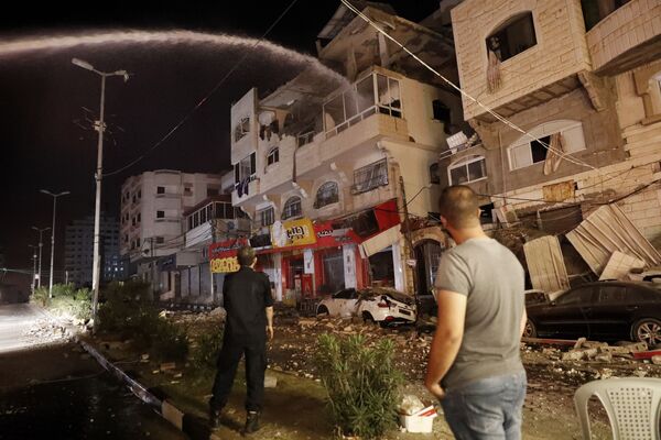 Bombeiros combatem incêndio em prédio após ser atingido pelos ataques aéreos israelenses, na cidade de Gaza - Sputnik Brasil