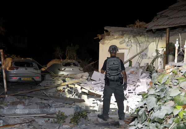 Oficial israelense inspeciona os danos em uma casa atingida por foguetes na cidade de Yehud, próximo de Tel Aviv, em Israel - Sputnik Brasil