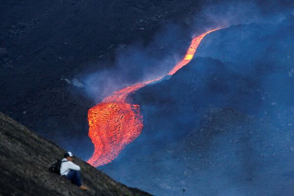Homem sentado enquanto rio de lava corre durante a erupção do vulcão Pacaya na Guatemala, 8 de maio de 2021 - Sputnik Brasil