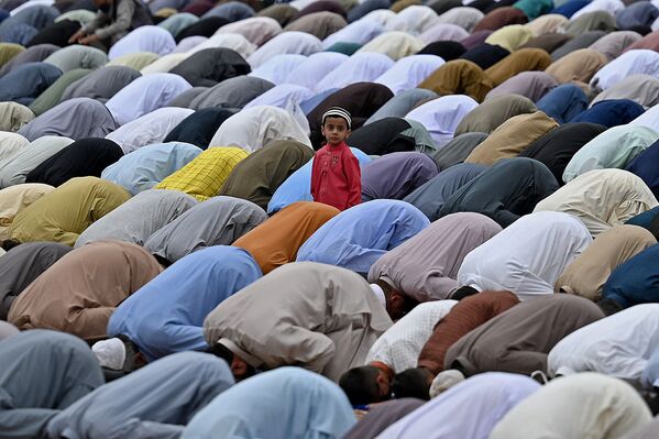 Criança olha para muçulmanos que rezam por ocasião do Eid al-Fitr, que marca o final do mês sagrado do Ramadã, na cidade paquistanesa de Rawalpindi, 13 de maio de 2021 - Sputnik Brasil