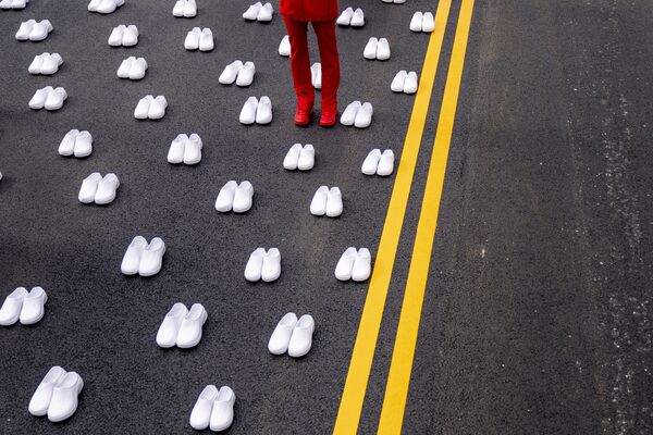 Mulher em uniforme de enfermeira, rodeada por centenas de pares de sapatos brancos representando as 402 enfermeiras que morreram da COVID-19, perto da Casa Branca em Washington, 12 de maio de 2021 - Sputnik Brasil